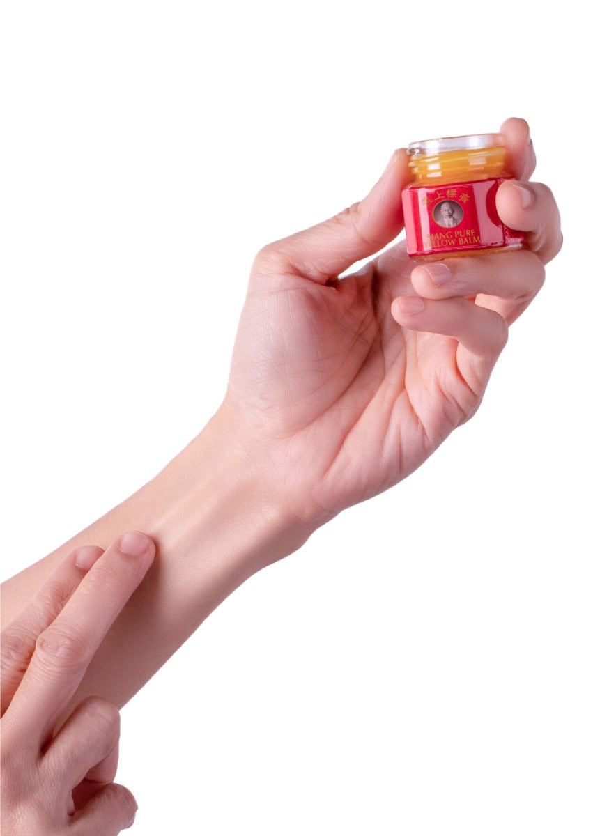 Hand holding a small jar of Siang Pure Yellow Balm