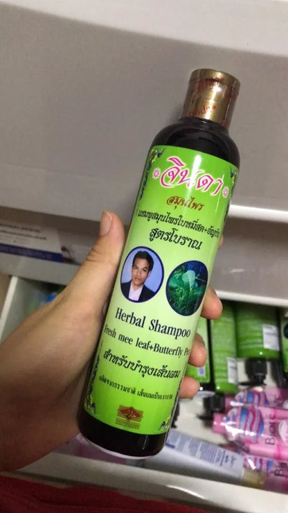 Jinda Herbal Shampoo bottle held in hand showing authentic Thai herbal packaging