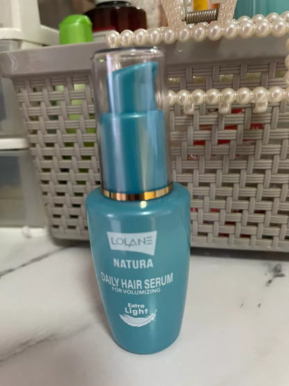 Lolane Natura Hair Serum for volumizing extra light 50ml in a blue bottle on a marble surface.