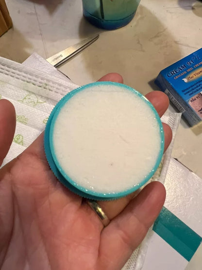 Close up of the white interior of the NICHIDI Cracked Skin Cream in the blue jar being held in a hand
