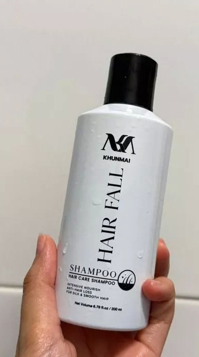 KHUNMAI Hair Fall Shampoo bottle held in hand showing front label