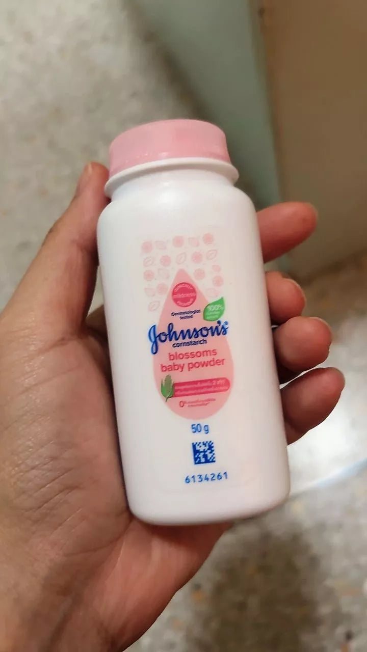  Side view of Johnson's Blossoms Baby Powder held in hand showing usage instructions