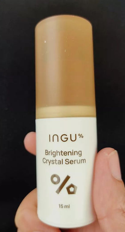 Hand holding INGU Brightening Crystal Serum showing the compact bottle design