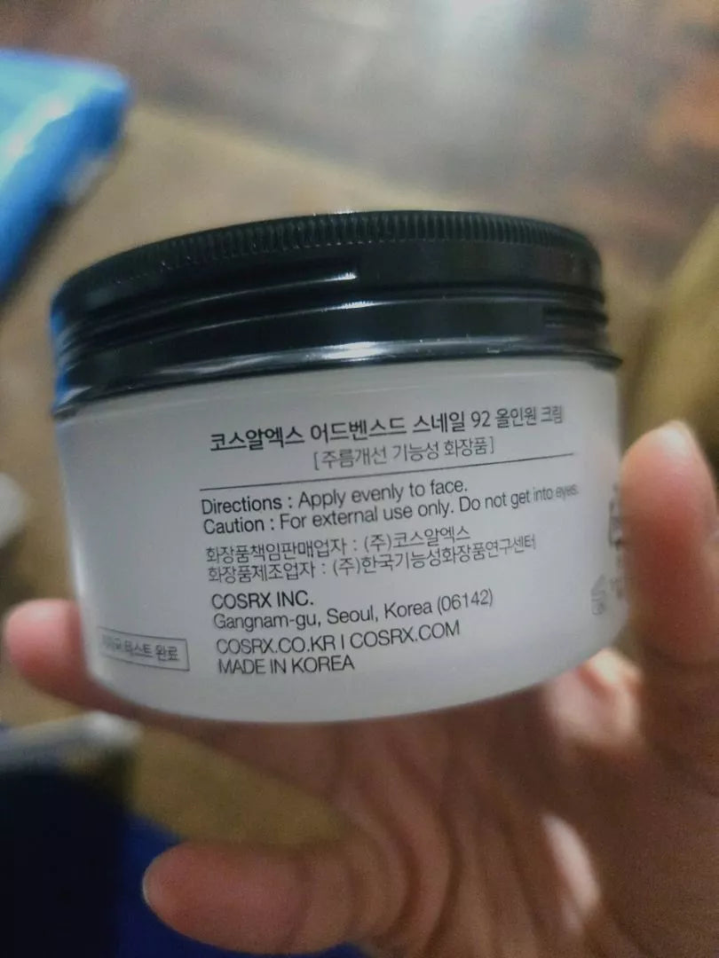 Hand holding COSRX Advanced Snail Mucin 92 All in One Cream jar front label
