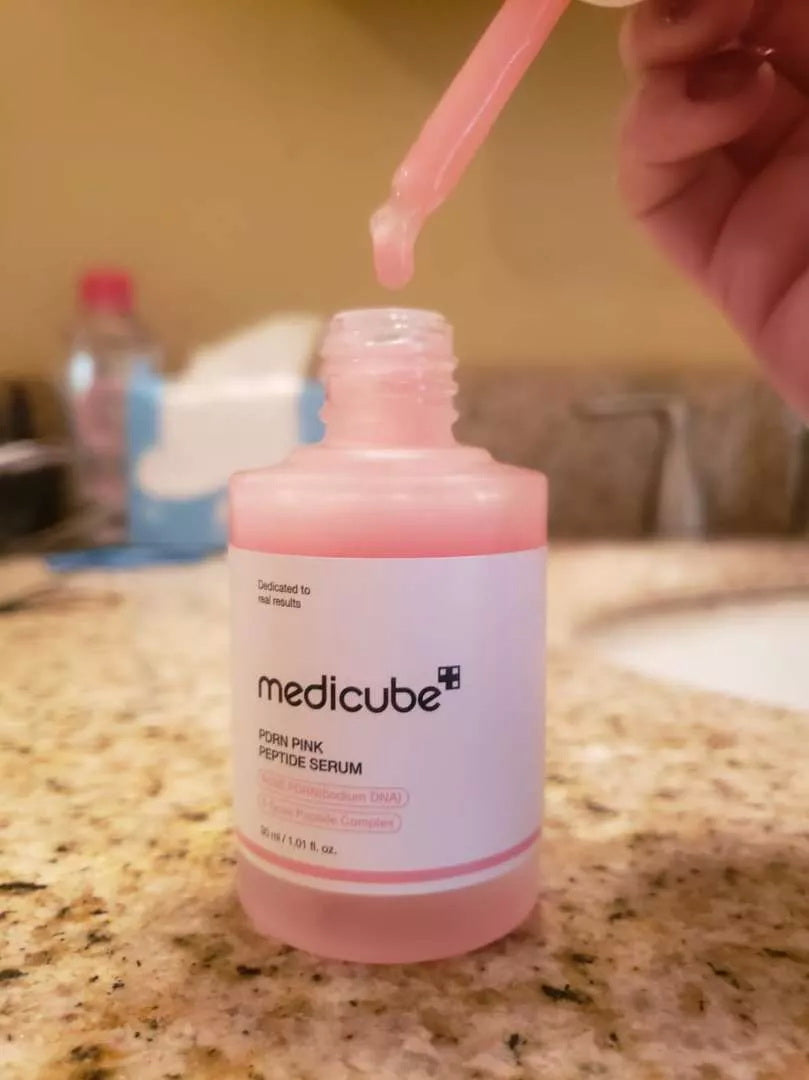 Using dropper of Medicube PDRN Pink Peptide Serum 30ml on table
