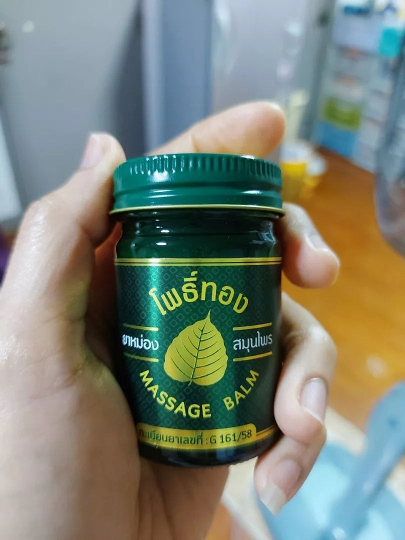 Hand holding Pho Thong Green Herbal Massage Balm 50g jar