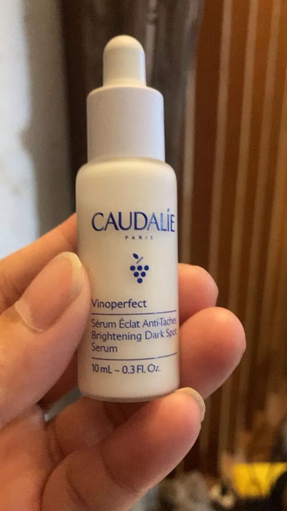 Hand holding Caudalie Vinoperfect Serum bottle in natural lighting