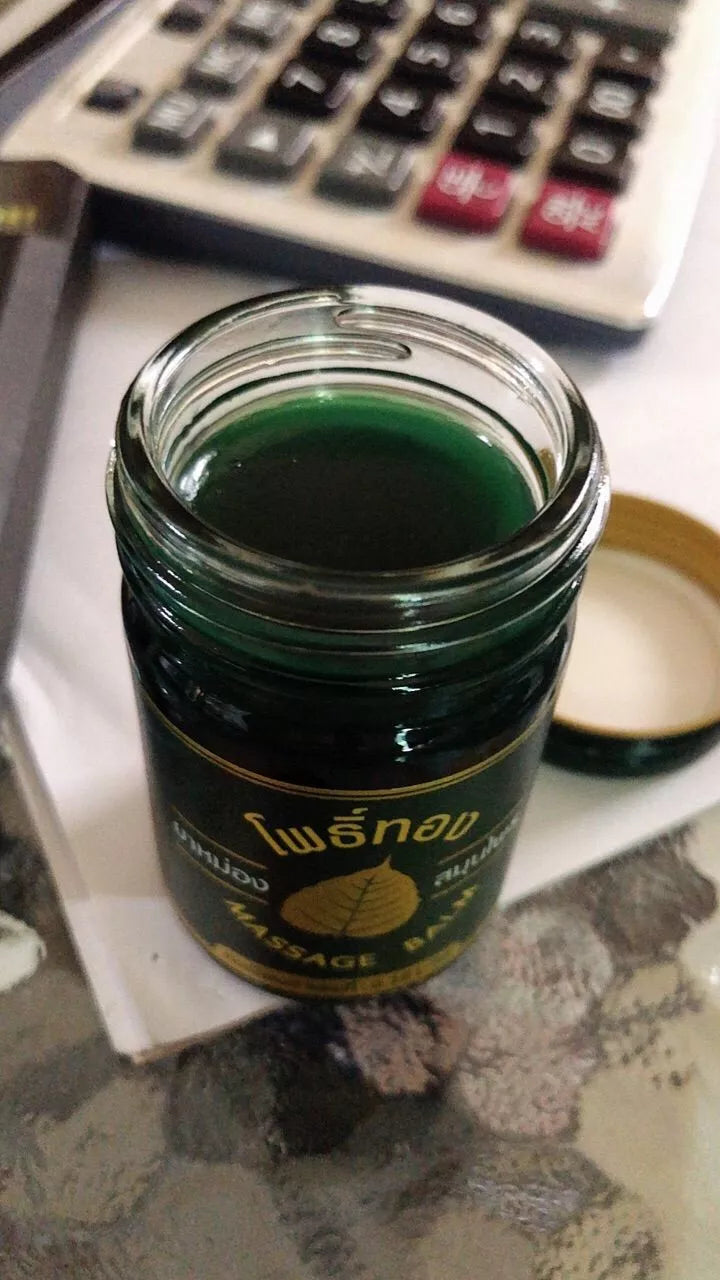 Open Pho Thong Green Herbal Balm jar showing green balm inside on table
