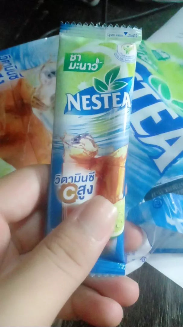 Hand holding NESTEA Lemon Iced Tea Mix Powder sachets Thai instant drink