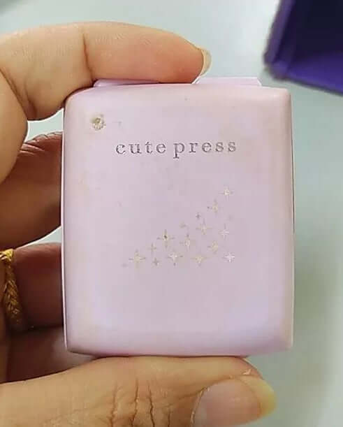 Hand holding the top view of a closed light purple compact of Cute Press Evory Retouch