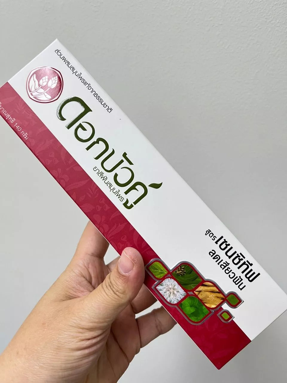 Hand holding the Twin Lotus Sensitive Toothpaste Dok Bua Ku box packaging
