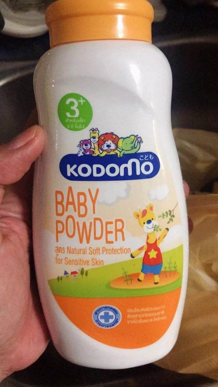 Product image of Kodomo Baby Powder 3+ with a blurred hand holding it.