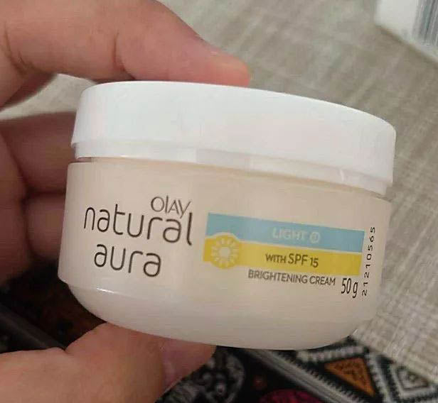 Close up of Olay Natural Aura Cream jar held in hand showing texture and label