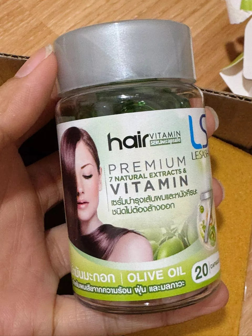 Hand holding Lesasha Hair Vitamin Serum Capsule Olive Oil jar close up