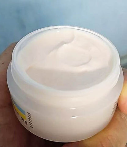 Open jar of Olay Natural Aura Cream showing the smooth white cream texture held in hand