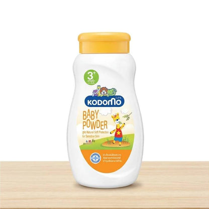 Kodomo Baby Powder 3+ orange bottle on a wooden shelf, white background.